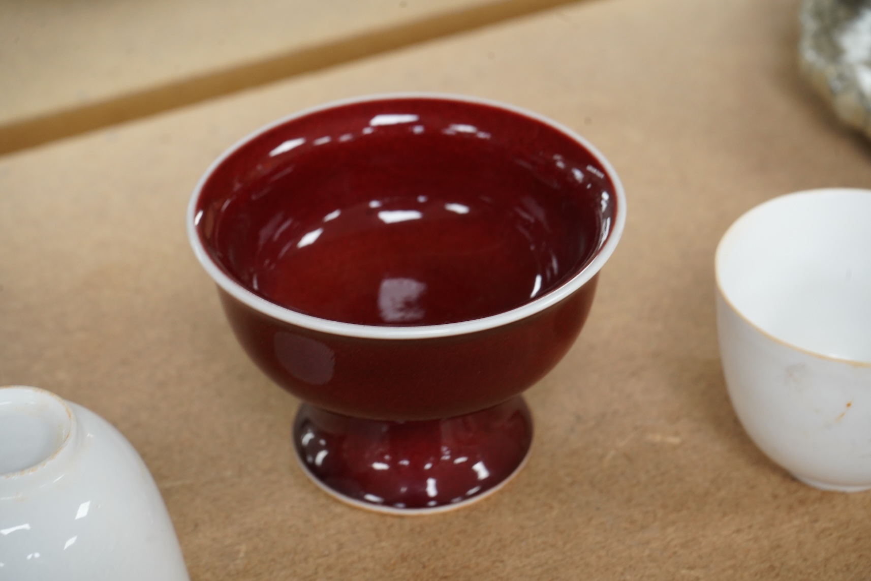 A Chinese red glazed stem cup together with two white glazed tea bowls, tallest 6.5cm